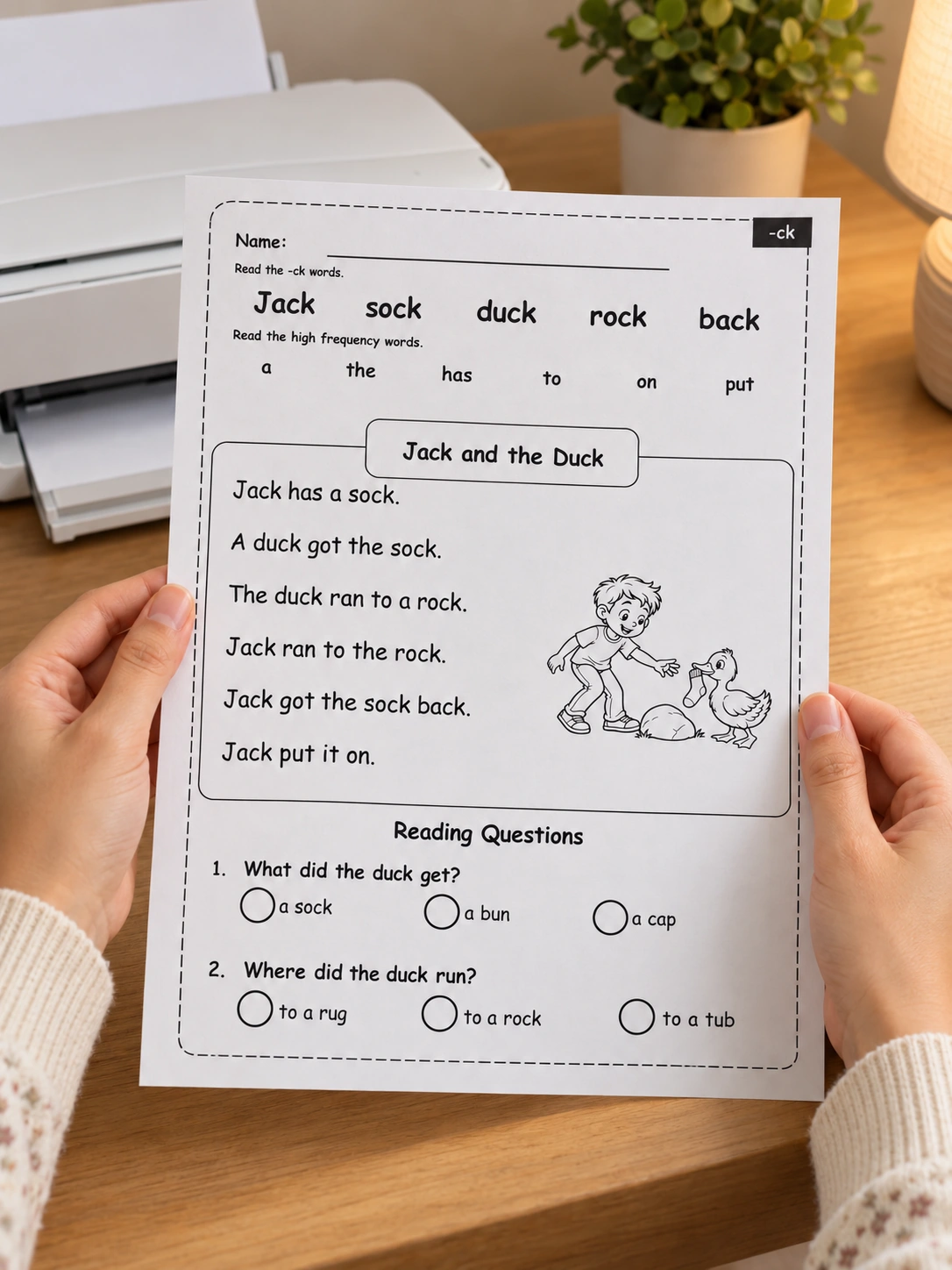 Hands holding the complete Jack and the Duck reading page beside a printer